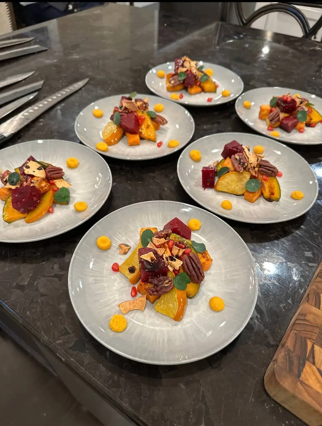 A course of roasted squash, cured beet, pecan and nasturtium plated by Chef Josh