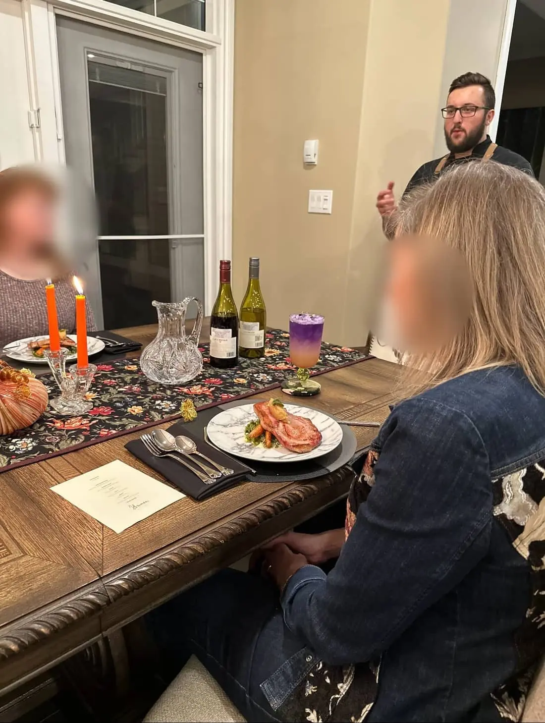Chef Josh presenting a course to guests at a candlelit table